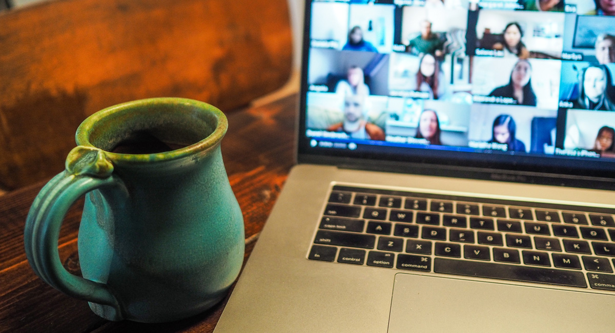 Coffee mug and laptop displaying an online meeting.