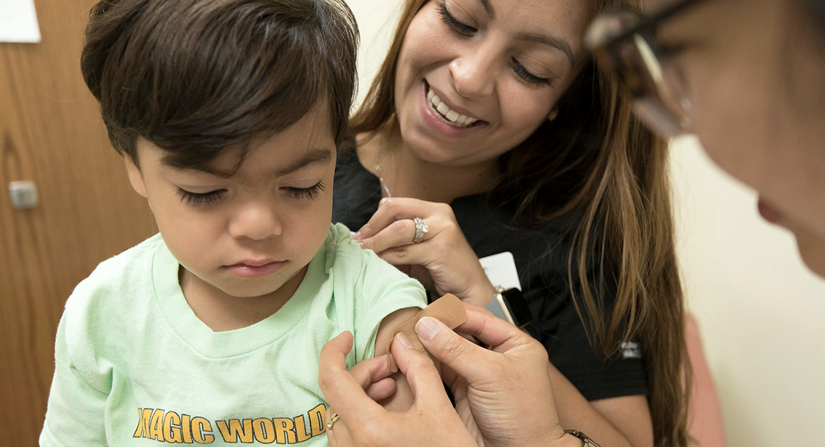 A doctor putting a bandage on a child's arm with mother.