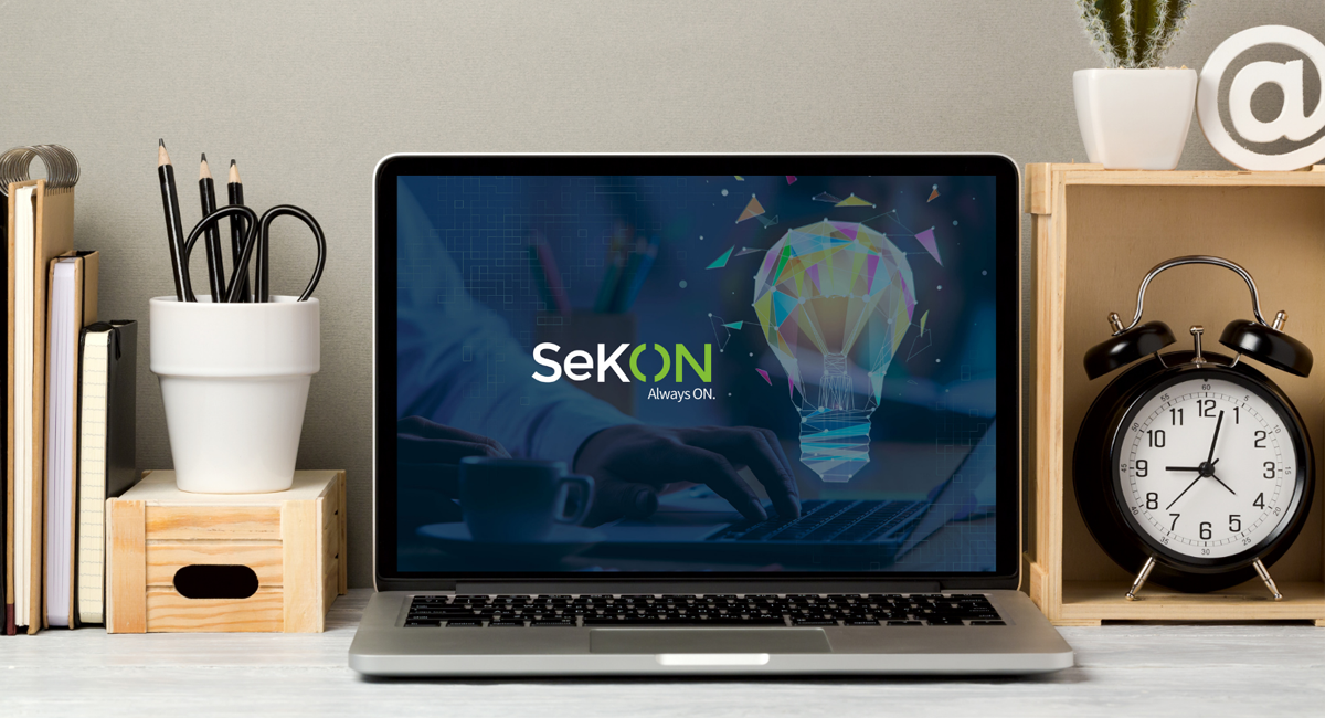 A laptop on a desk showing Sekon logo.